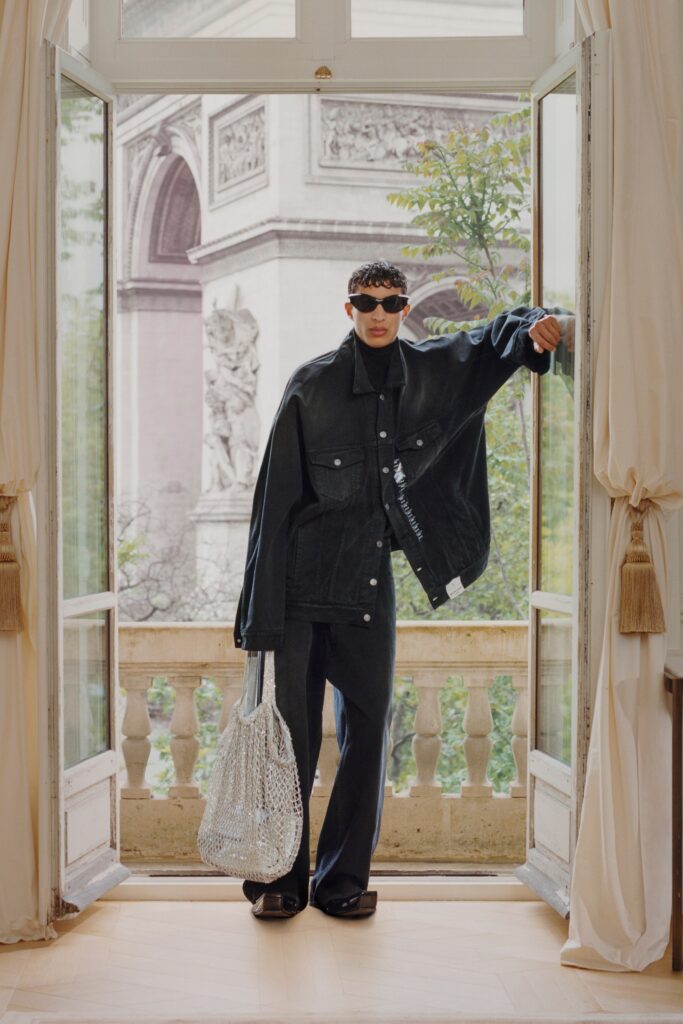 A relaxed black denim jacket with long sleeves and collared design paired with wide-leg pants.