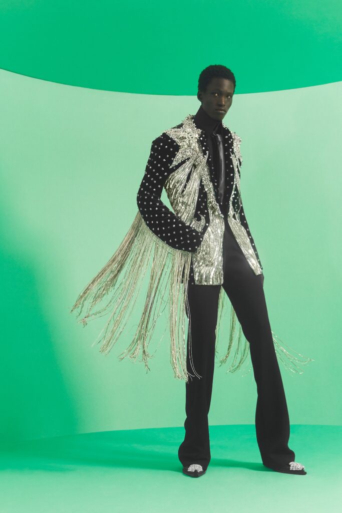 A tailored black sequined jacket with fringed details paired with sleek black pants.