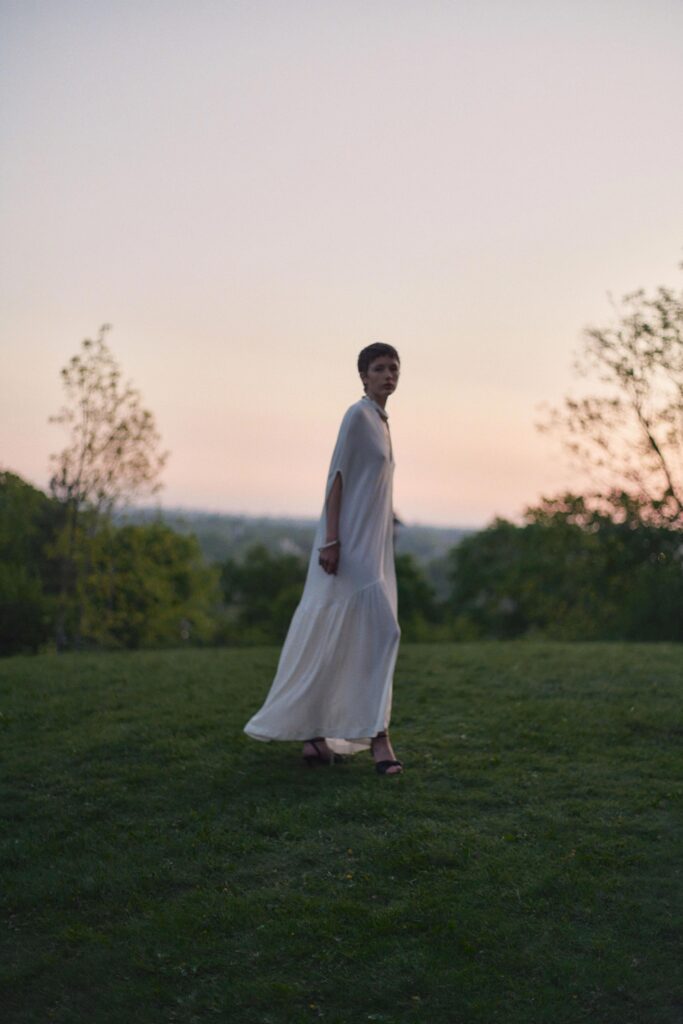 A relaxed white silk dress with a high neckline and tiered design, perfect for elegant occasions.
