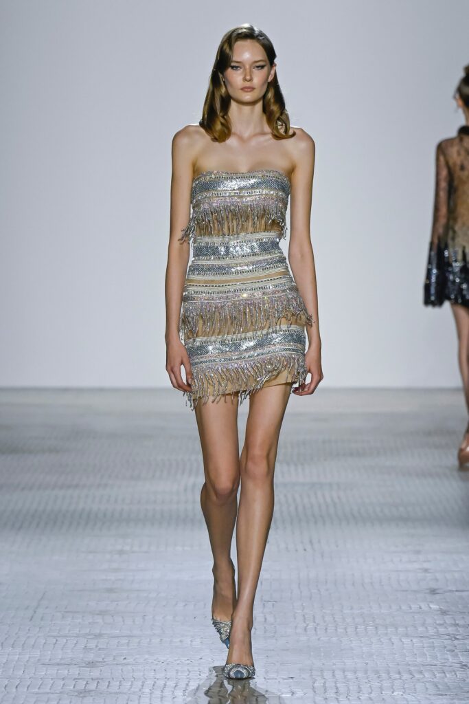 A fitted silver strapless dress adorned with fringes for a glamorous look.