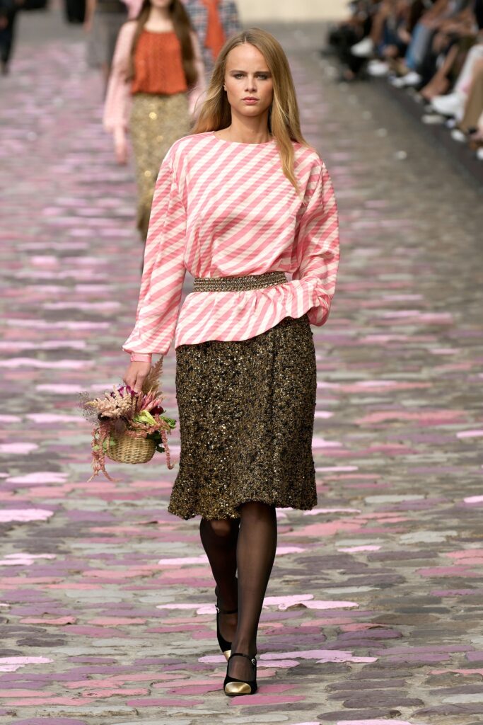 A relaxed pink striped long-sleeve top paired with a tiered gold sequined skirt.