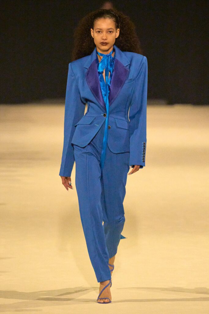 A tailored blue suit with long sleeves and a collared design, featuring button details.