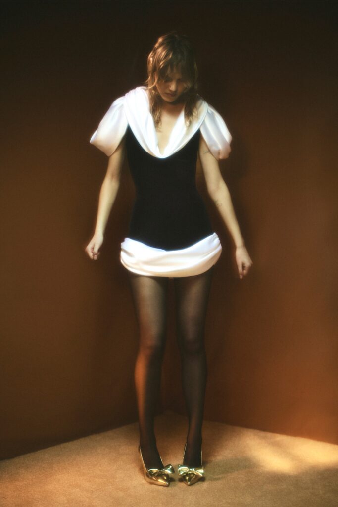 A fitted black and white dress with a V-neckline and asymmetric design details.