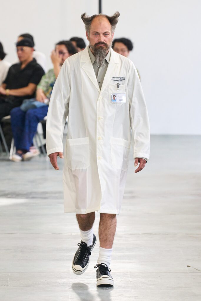 A relaxed white cotton coat with long sleeves and a collared design, featuring button details.