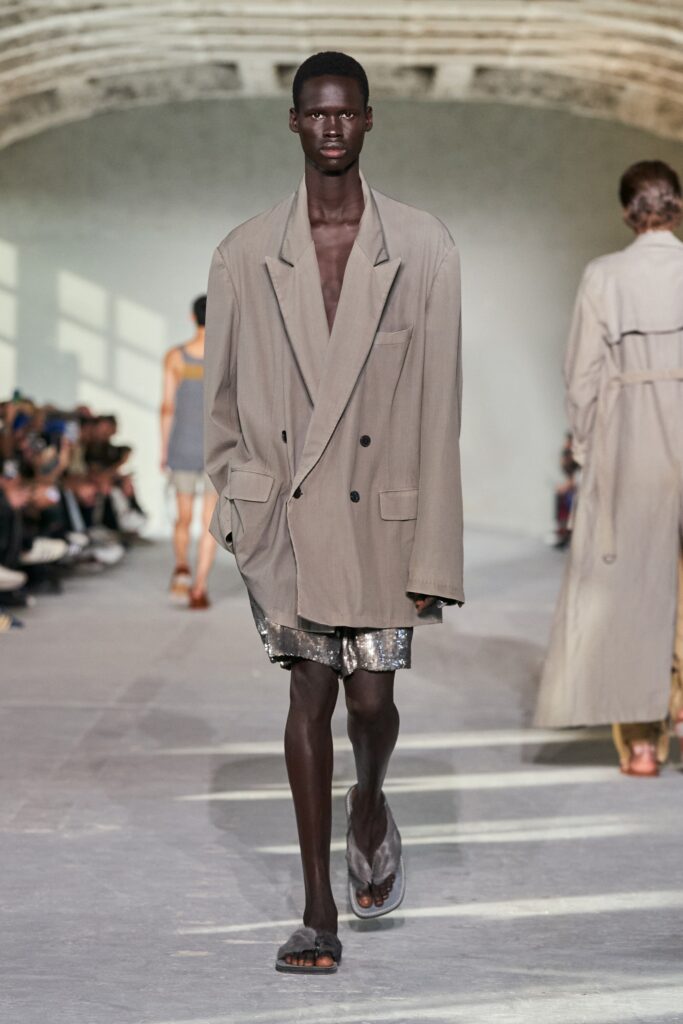 An oversized gray cotton jacket with long sleeves and collared design paired with shorts.