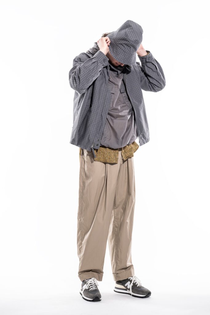 A relaxed gray hooded jacket paired with beige pants featuring a buttoned design.