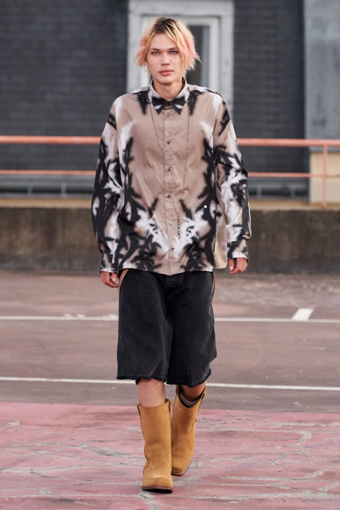 A relaxed-fit printed long-sleeve shirt paired with wide-leg black denim shorts.