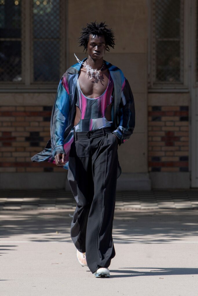 A relaxed blue cotton long-sleeve shirt with a V-neck and asymmetric design paired with black pants.