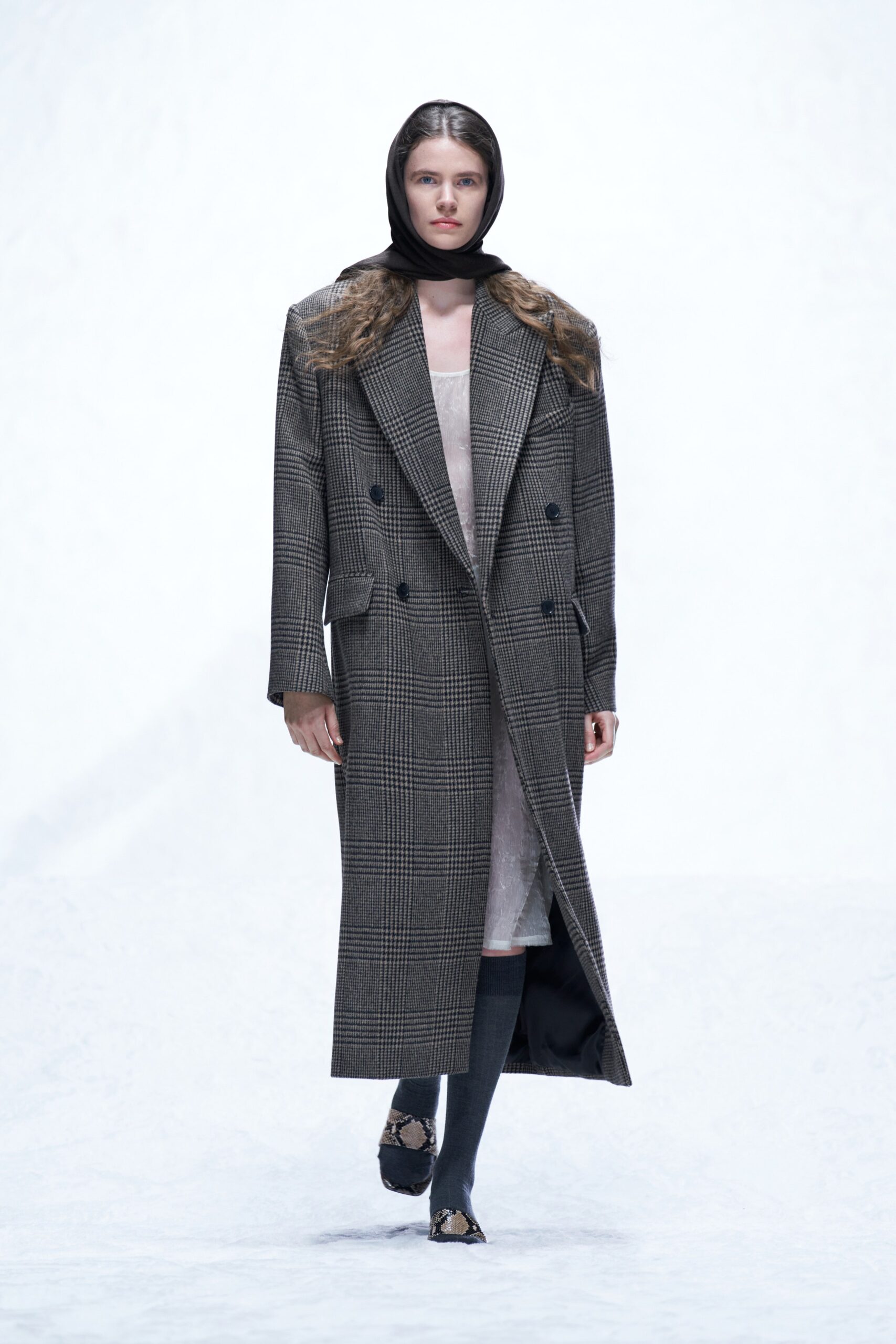 A fitted gray checked coat layered over a dress, featuring a long-sleeve and collared design.