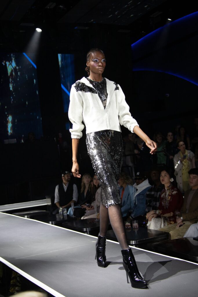 A fitted black sequin pencil skirt paired with a white long-sleeve top featuring a V-neckline.