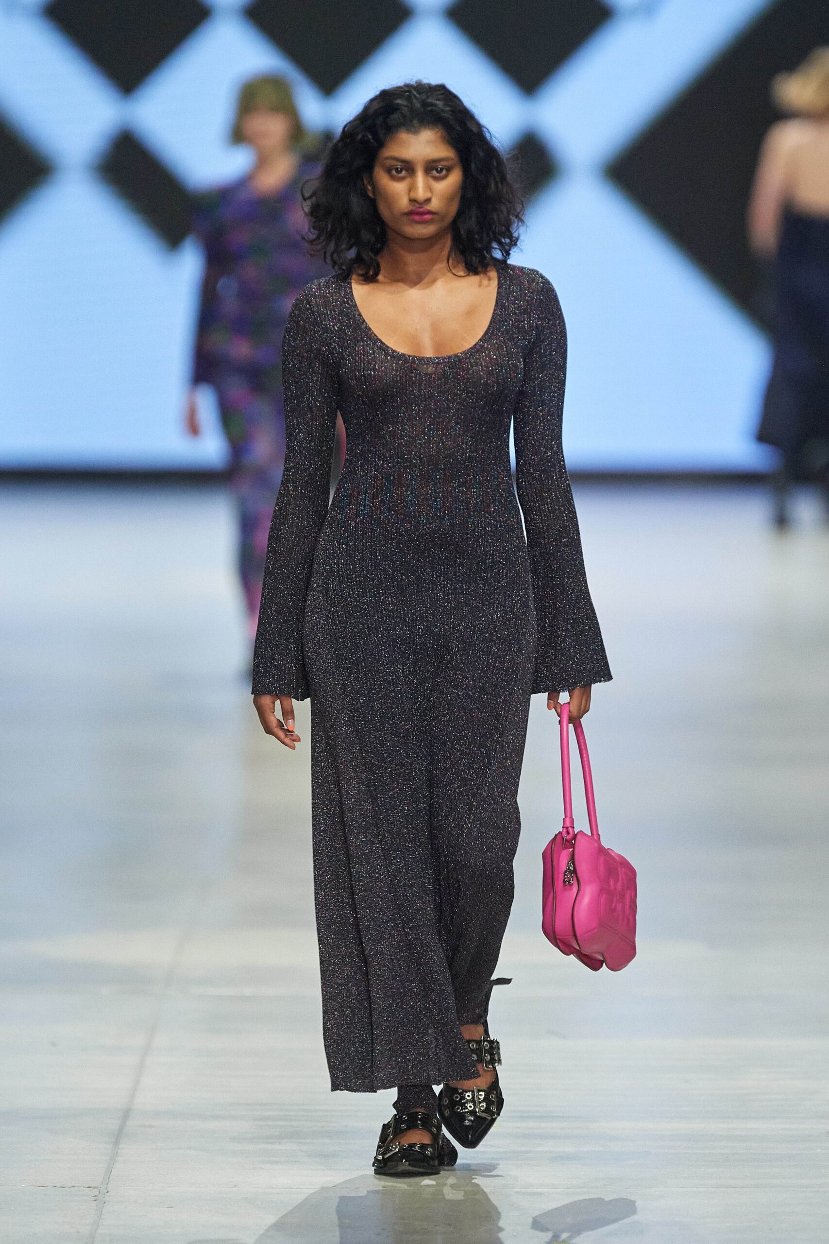 A fitted black knit dress with a V-neckline and long sleeves featuring a slit detail.
