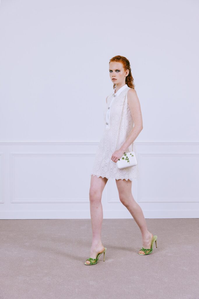 A fitted white sleeveless dress with a collared neckline and embroidered details.