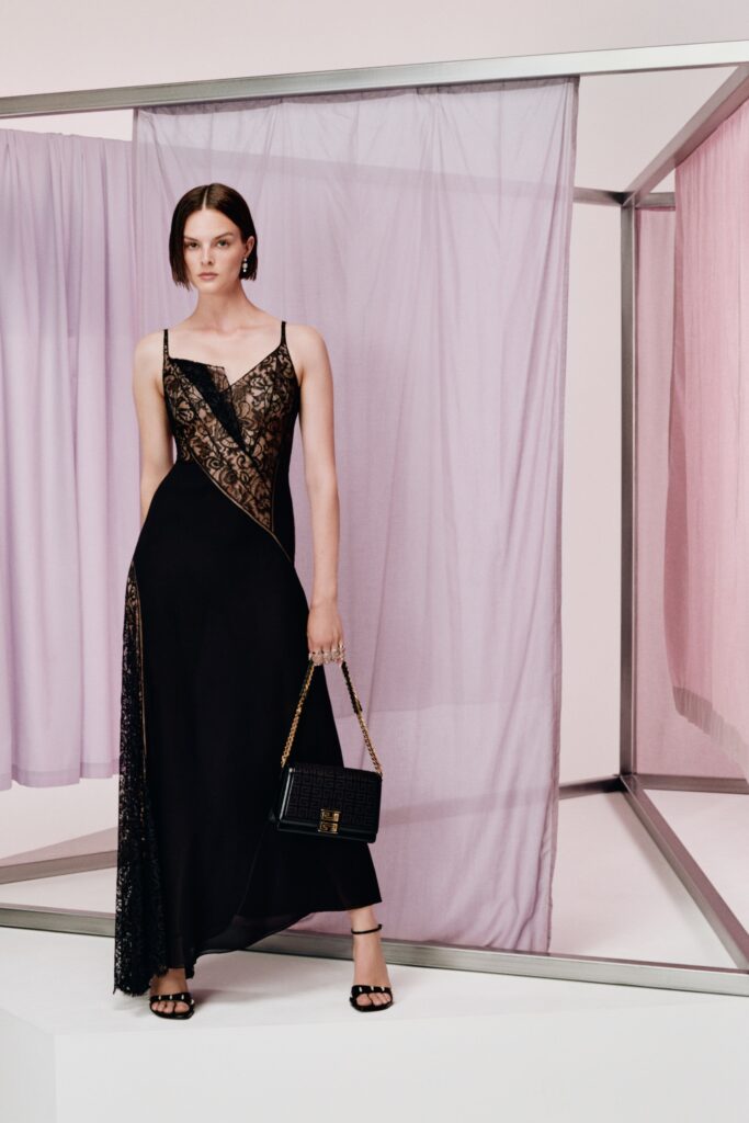 A fitted black silk dress with a V-neckline and asymmetric design detail.