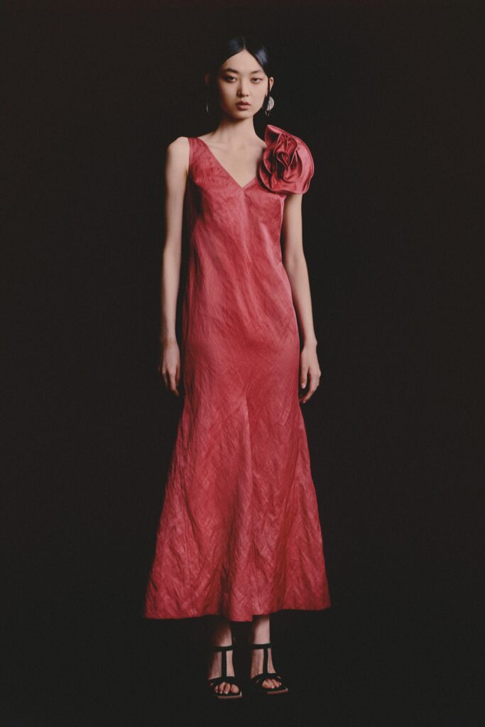 A fitted red silk dress with a sleeveless design and an asymmetric floral detail.