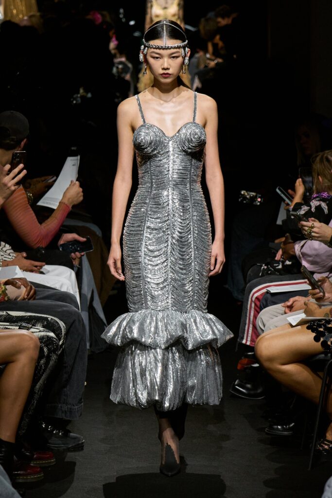 A fitted silver silk sleeveless dress with a V-neckline and tiered design.