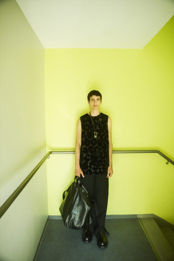 A fitted black leather sleeveless top paired with tailored black pants, showcasing a textured design.