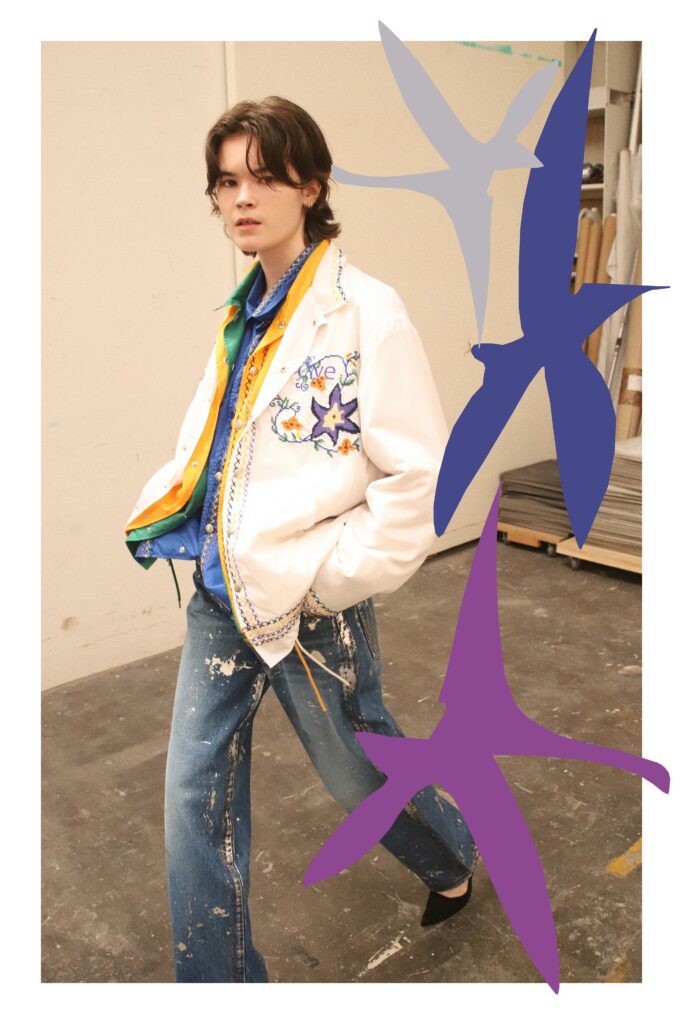 An oversized white jacket with blue embroidery paired with blue denim pants.