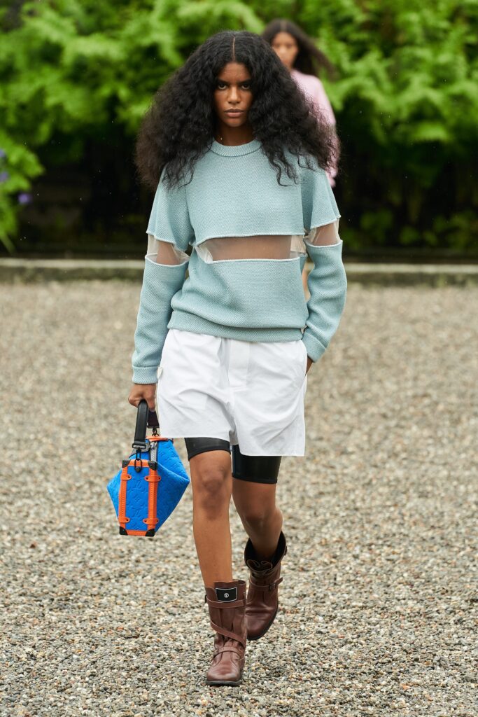 A relaxed blue cotton sweater with long sleeves paired with white shorts, featuring a layered design.