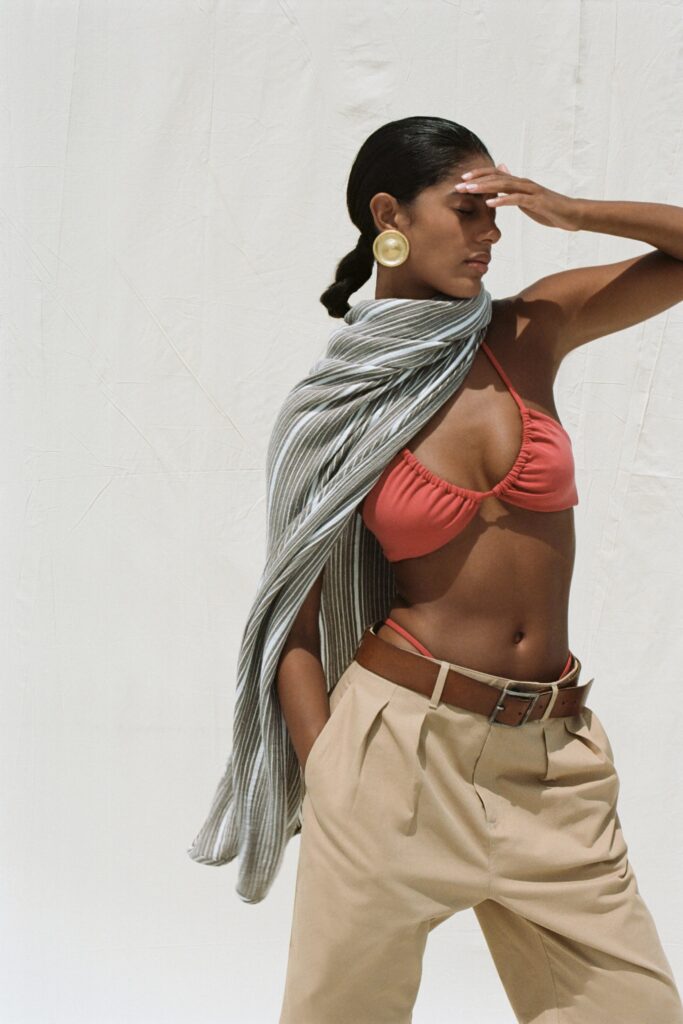 A relaxed red sleeveless top paired with high-waisted beige pants featuring a striped design.