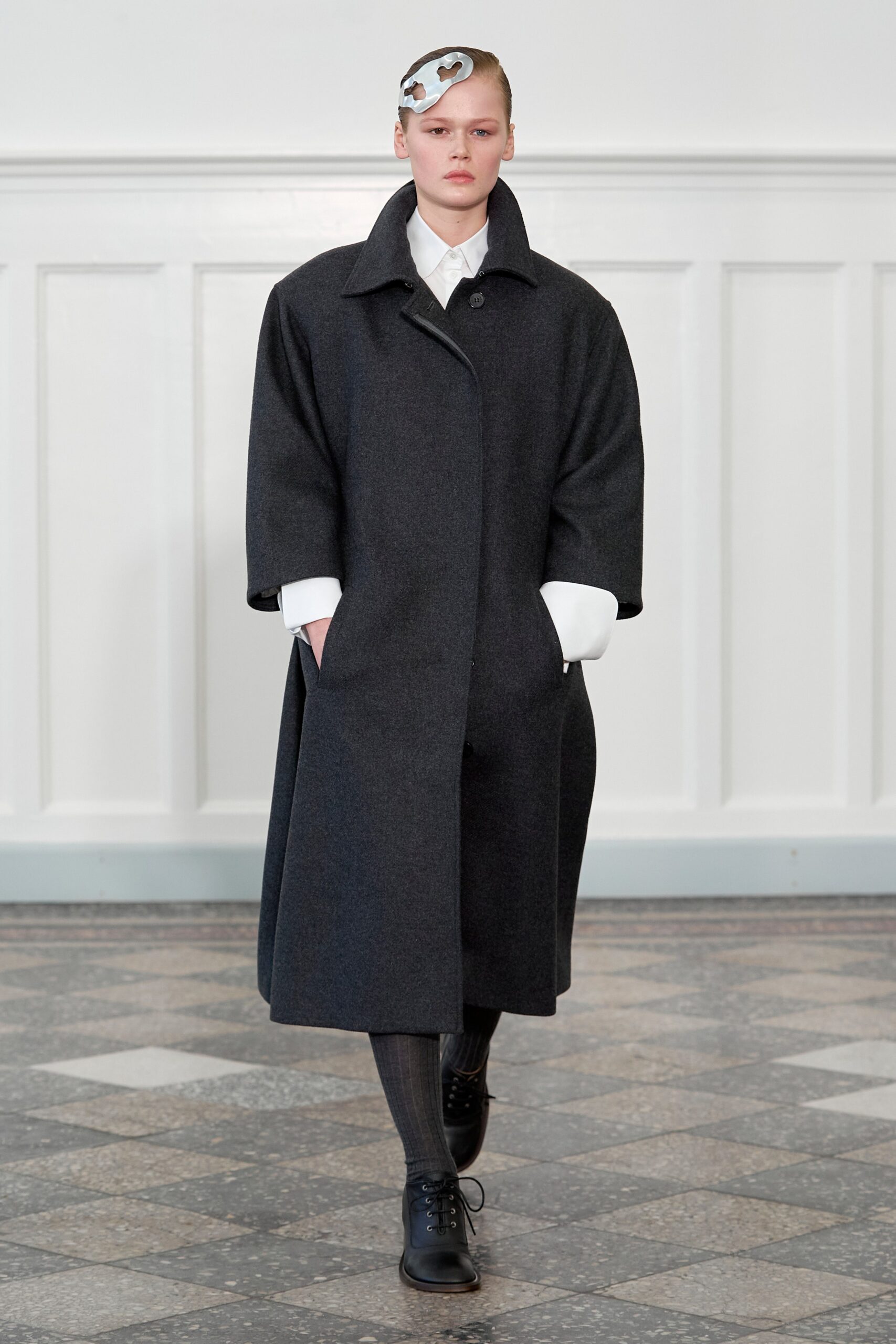 An oversized black wool coat with a collared neckline and buttoned front.