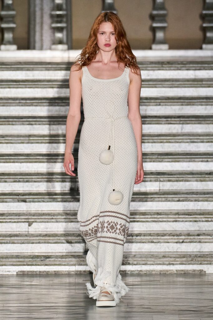 A fitted white cotton dress with a sleeveless design and tiered detailing.