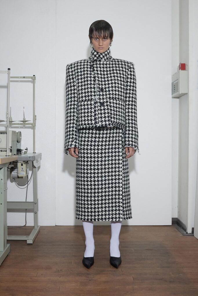 A fitted black and white checked blazer with a matching skirt, featuring long sleeves and a collared design.