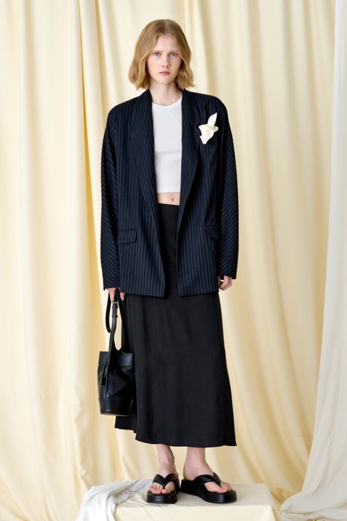 A fitted black striped blazer paired with a white crop top and a black maxi skirt.