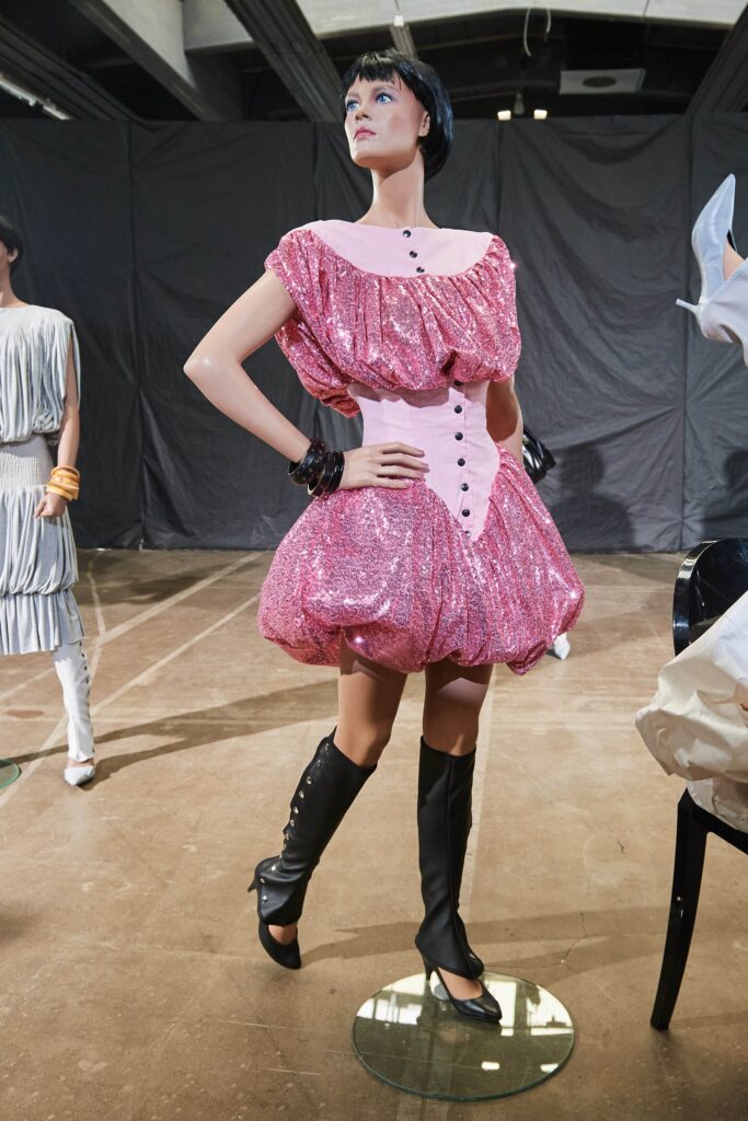 A fitted pink sequined dress with a ruffled design and sleeveless collar.