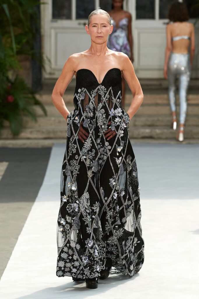 A fitted black strapless gown with intricate embroidery and a tiered design.