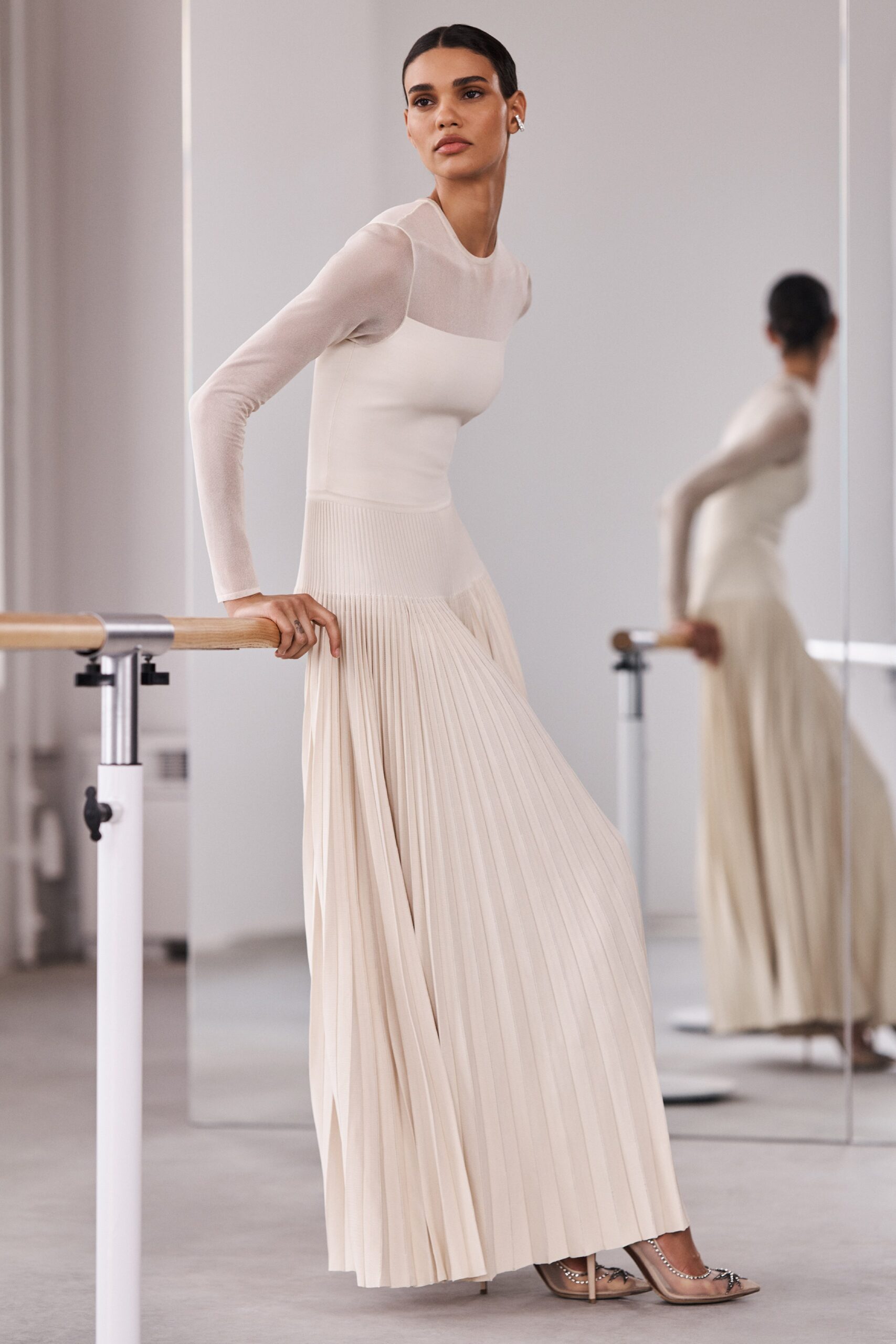 A fitted beige silk long-sleeve dress featuring a pleated design.