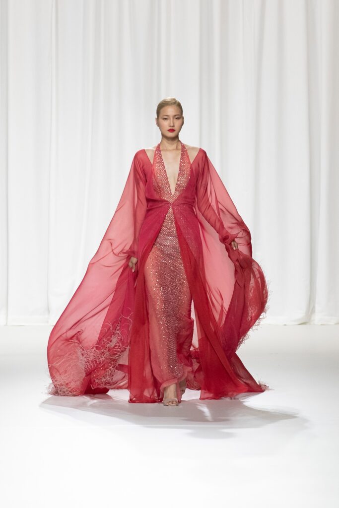A fitted red silk sleeveless gown with a V-neckline and layered design.