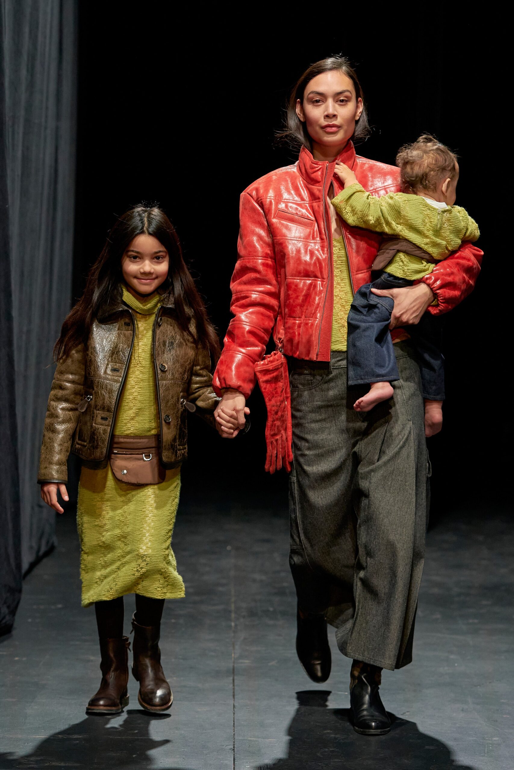 A fitted red leather long-sleeve jacket with a collared design and an asymmetric gray skirt.