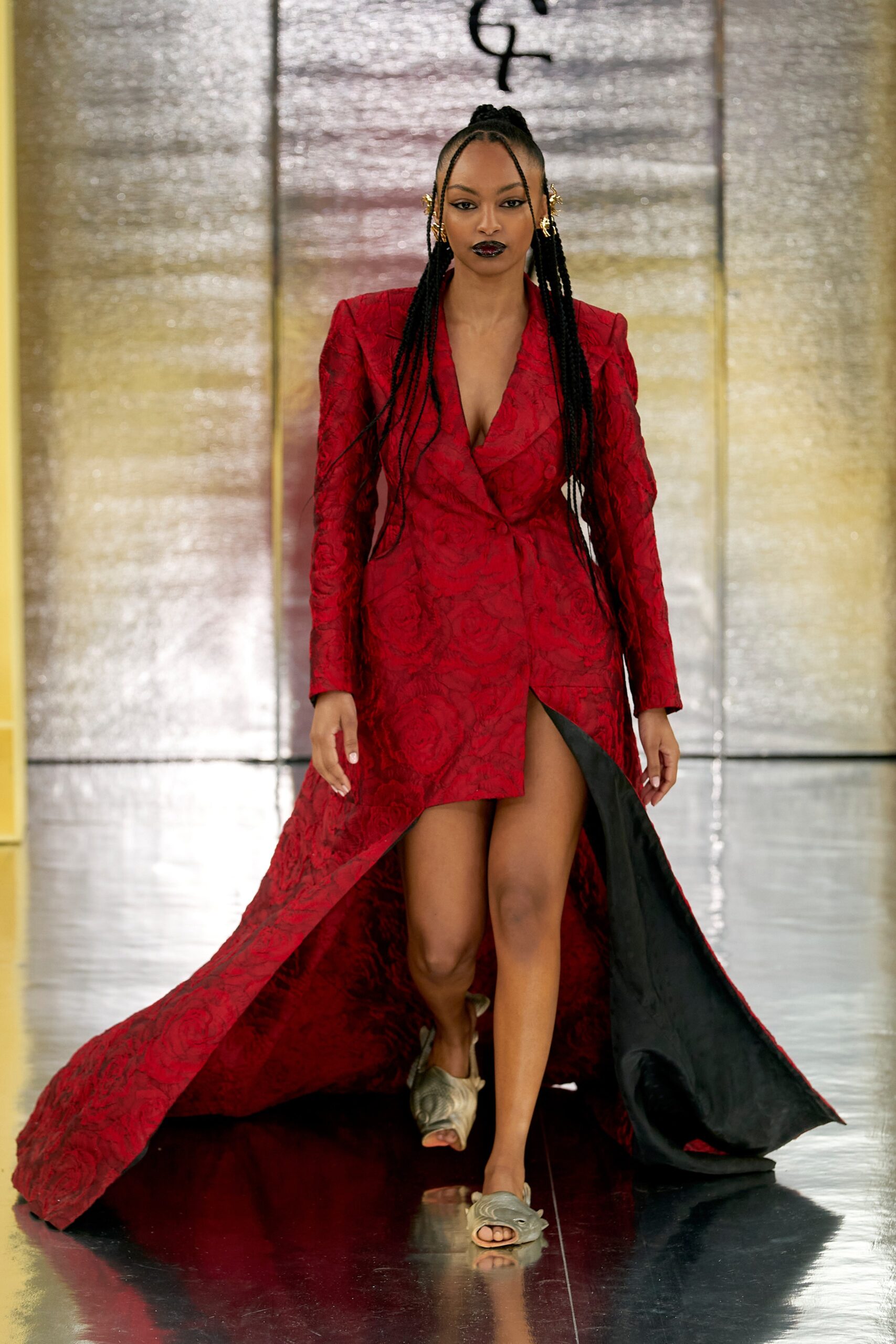 A fitted red silk dress with a V-neckline and an asymmetric silhouette featuring a slit.