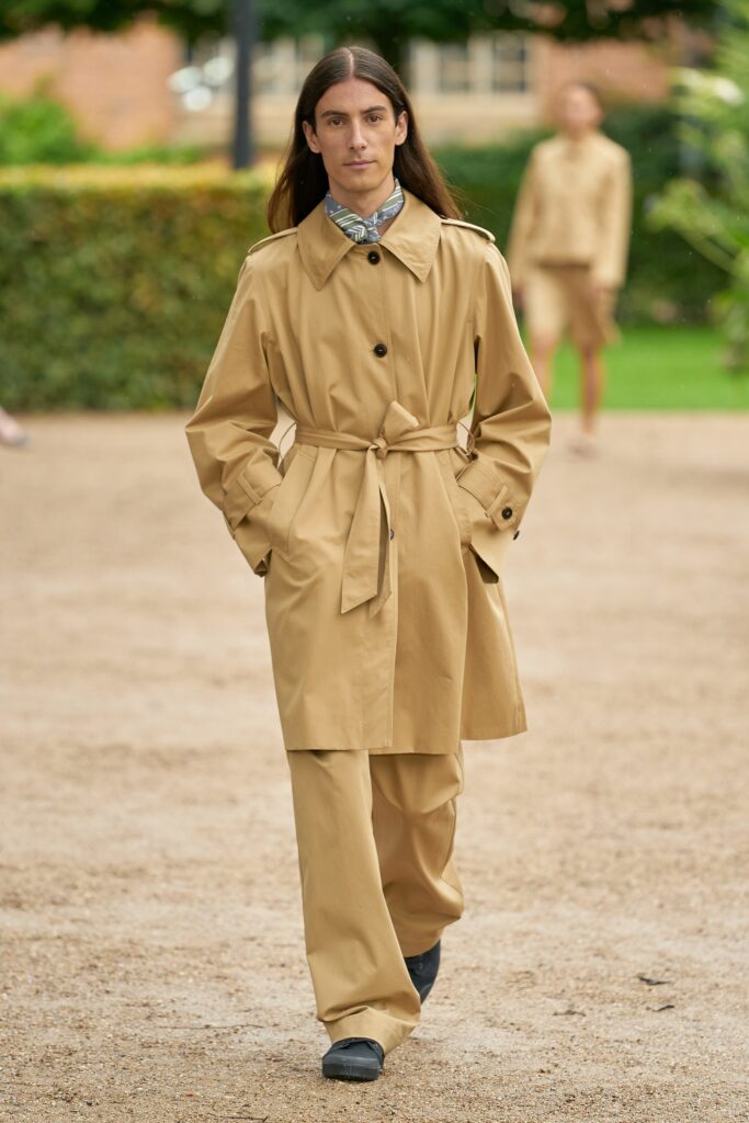A relaxed beige cotton trench coat with long sleeves and a belted design.