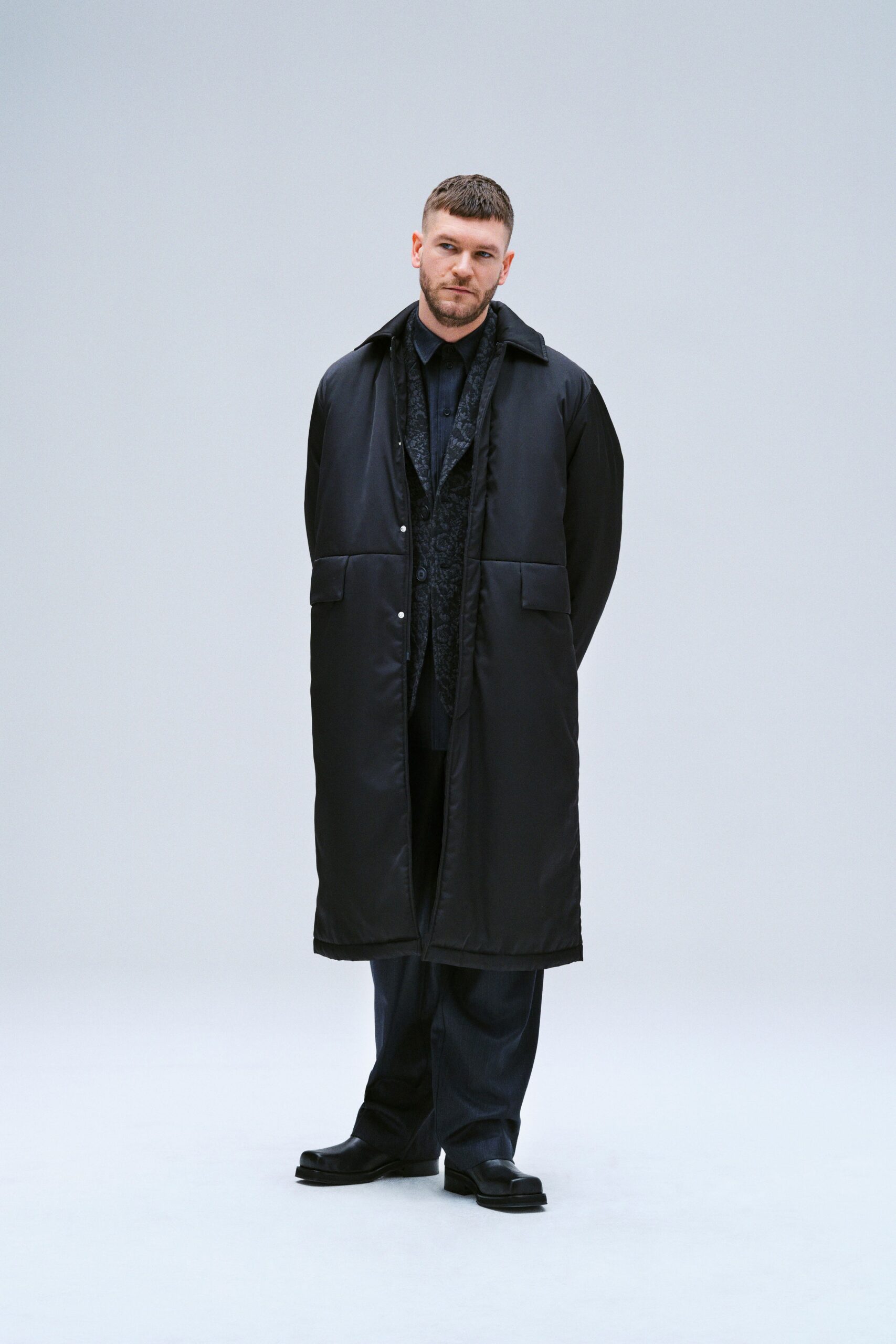 A relaxed black coat paired with straight-leg pants, featuring a collared long-sleeve design.
