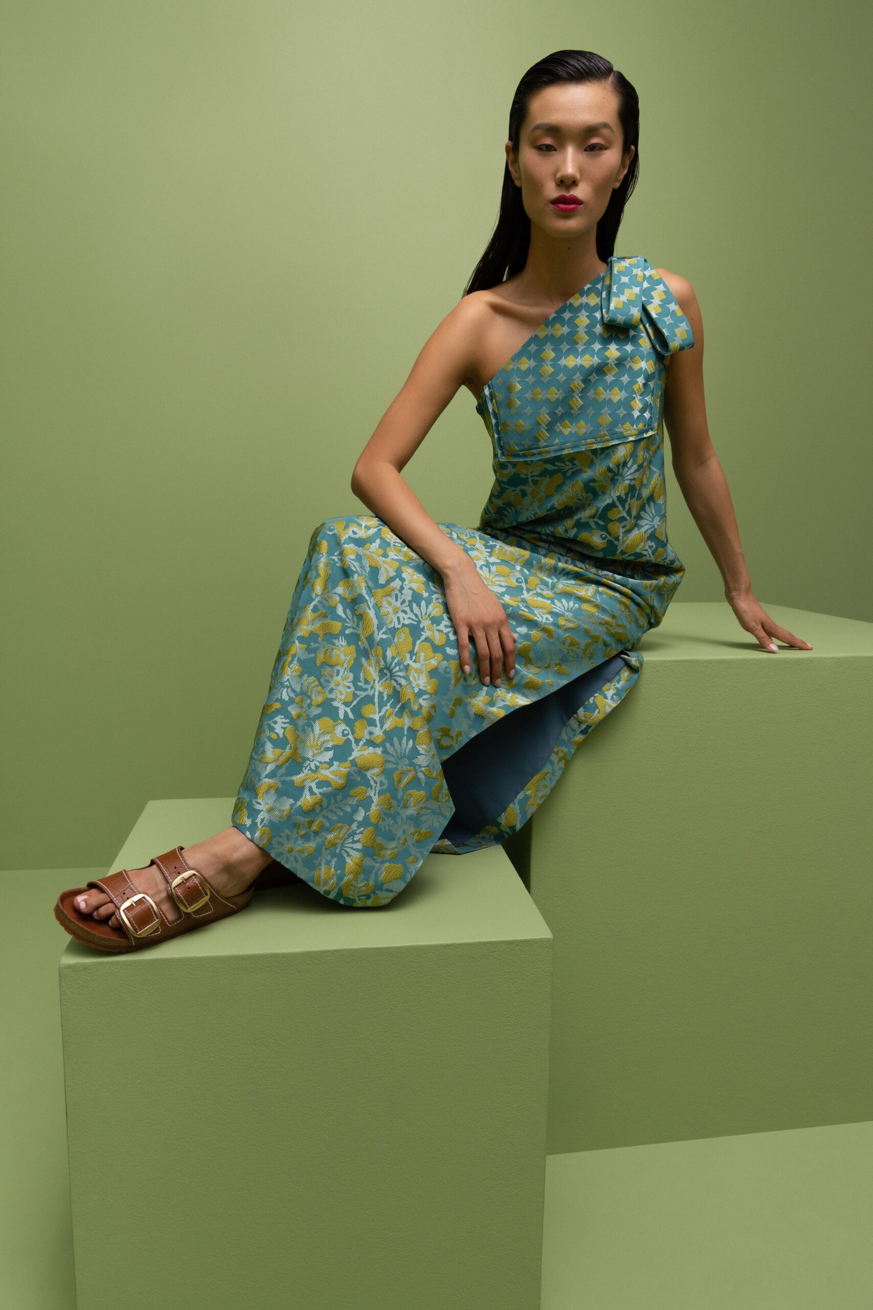 A fitted blue and green floral dress with a one-shoulder design.