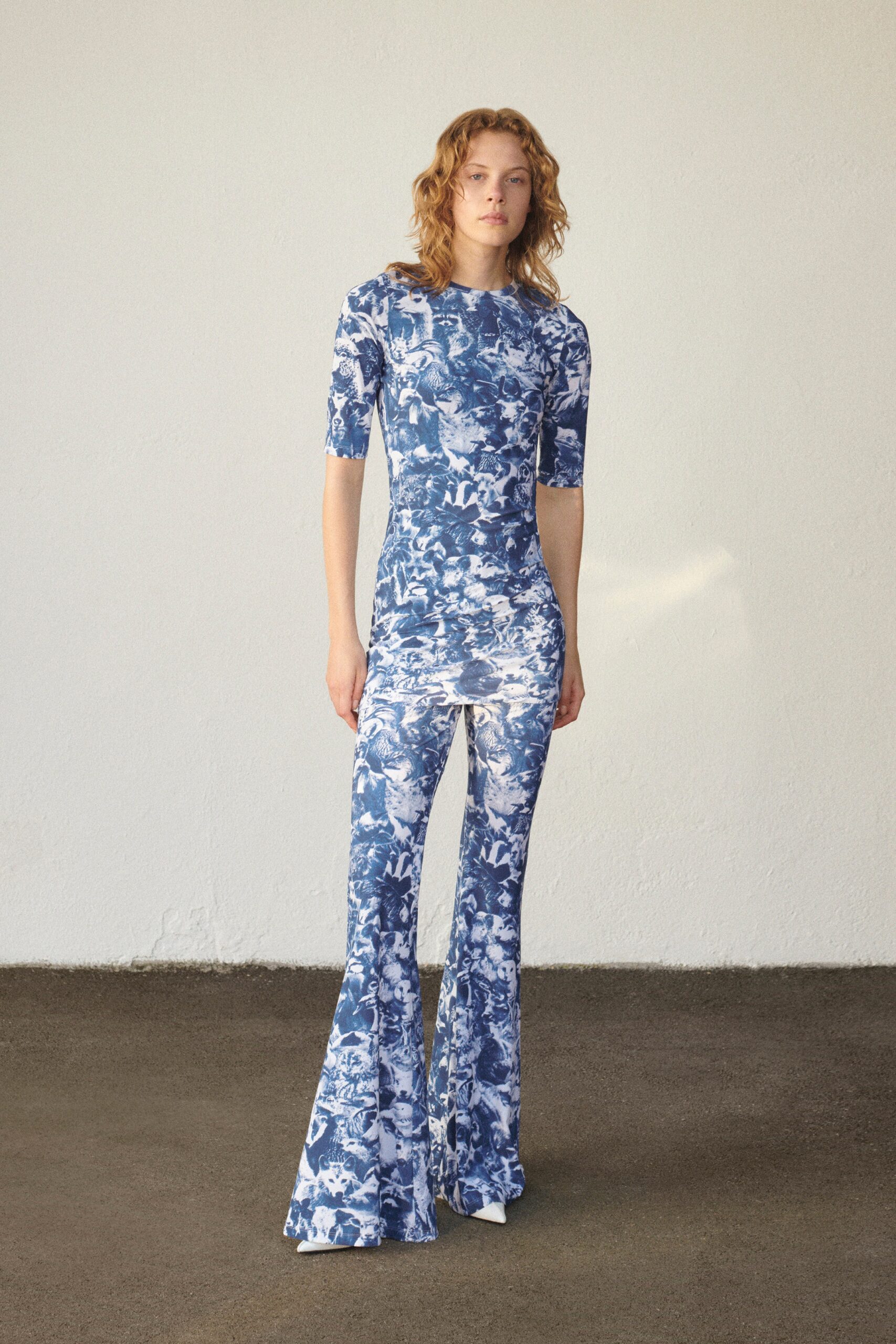 A fitted blue cotton jumpsuit with short sleeves and a high neckline, featuring flared legs.