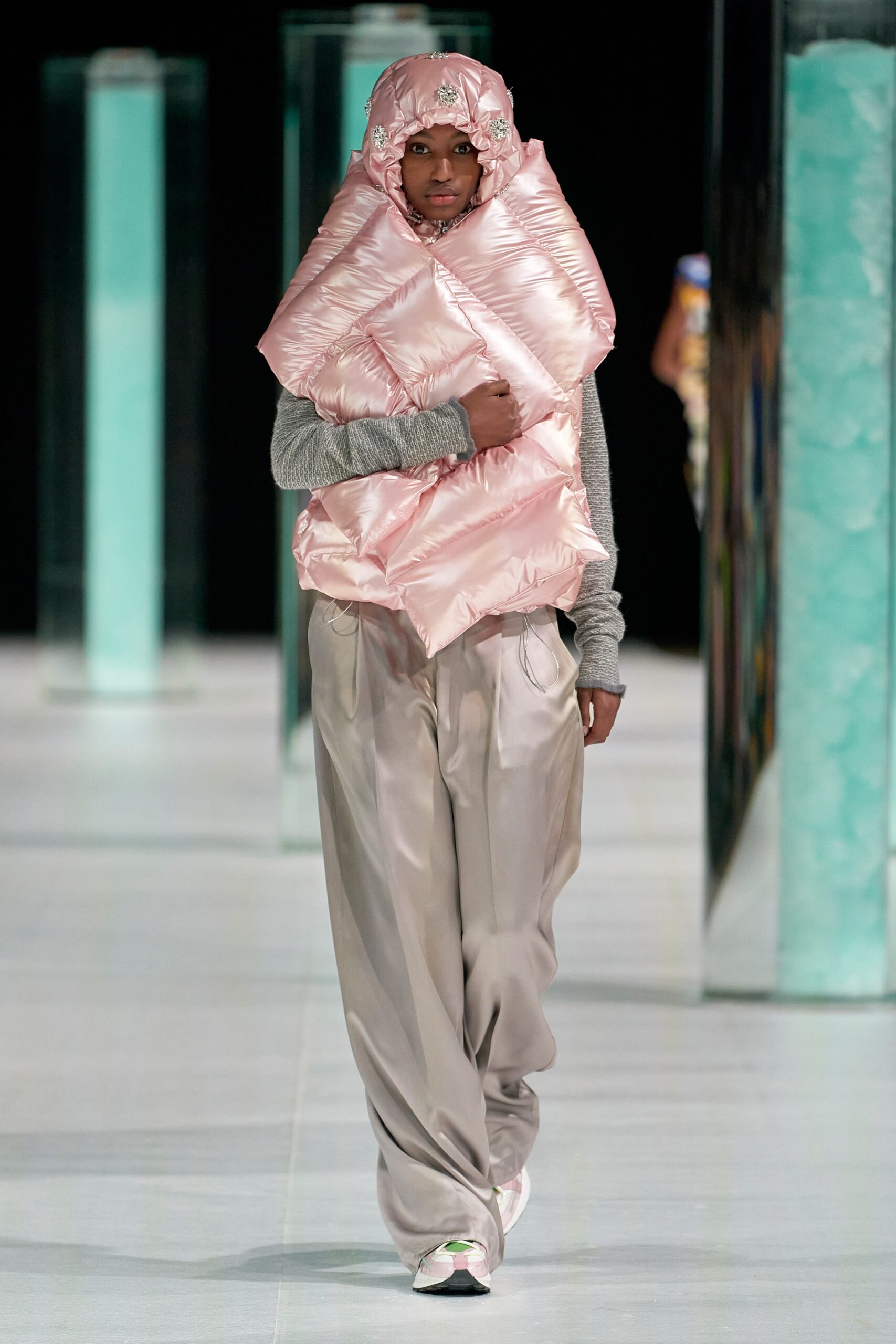 pink padded jacket with gray sweater and beige pants