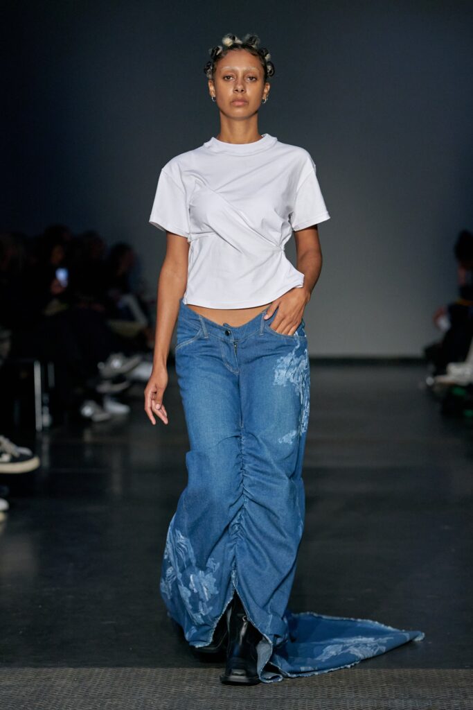 A fitted white cropped top with short sleeves paired with layered blue denim pants.