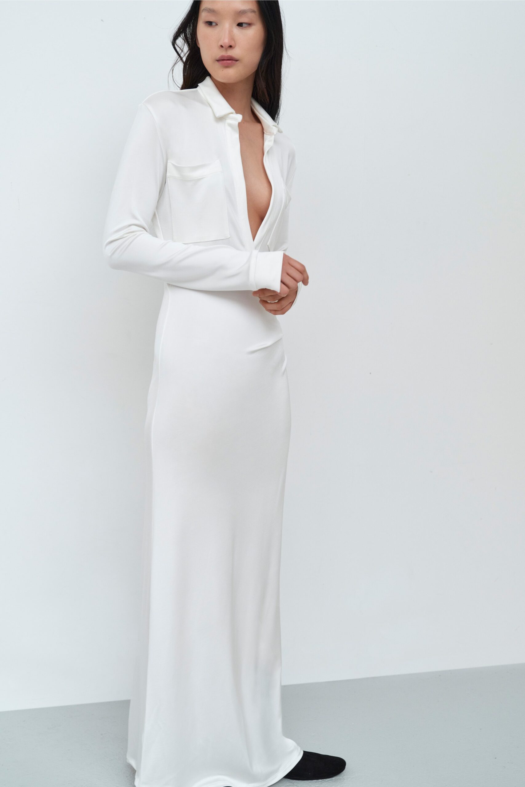 A fitted white silk dress with long sleeves and a deep V-neckline.