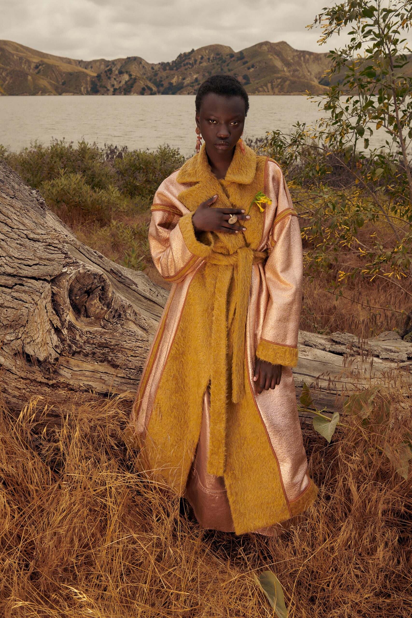 A relaxed gold and pink fur coat layered over a dress with long sleeves and a belted waist.