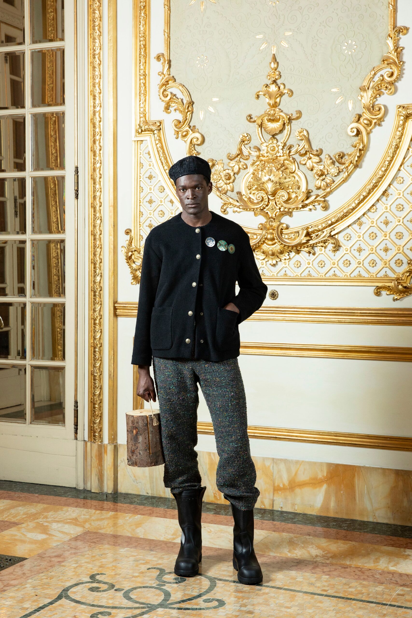 A relaxed black jacket with long sleeves and a collared design paired with multicolor straight-leg pants.