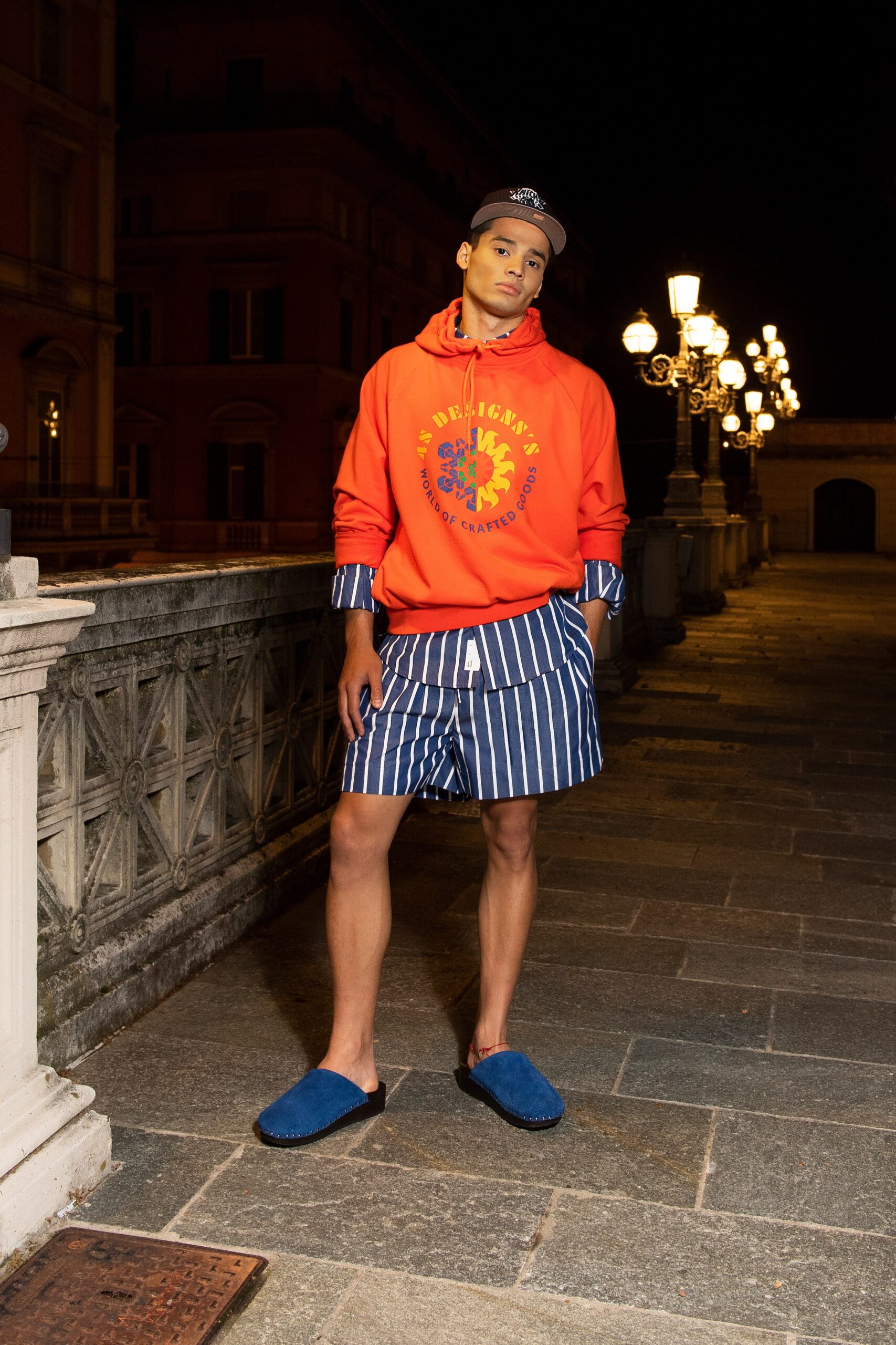 A relaxed orange cotton hoodie paired with striped shorts for a casual summer look.