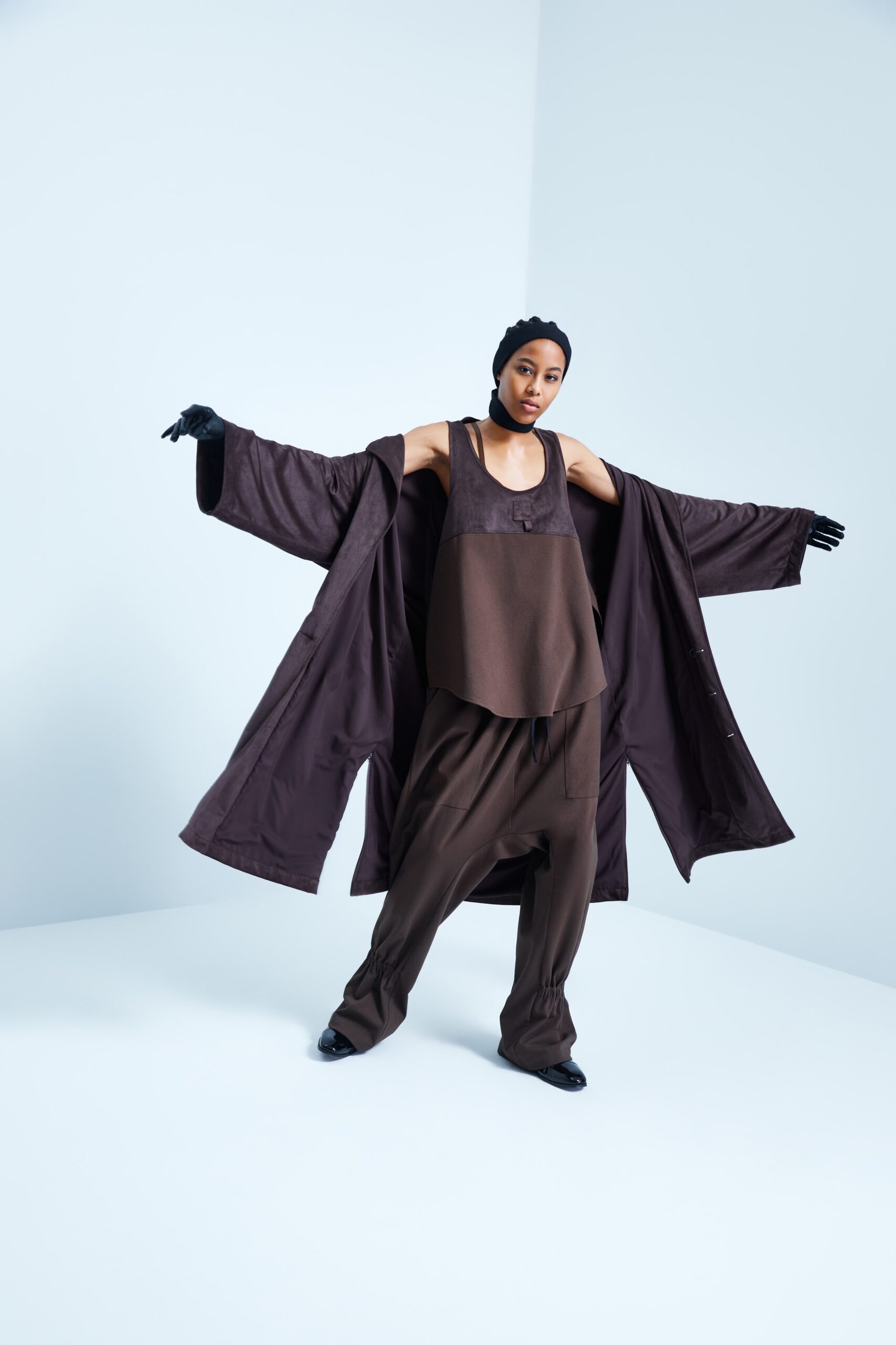 This ensemble features a relaxed coat layered over a sleeveless top, both in a rich brown hue. The open silhouette of the coat creates a sense of movement, while the understated design allows for versatile styling.