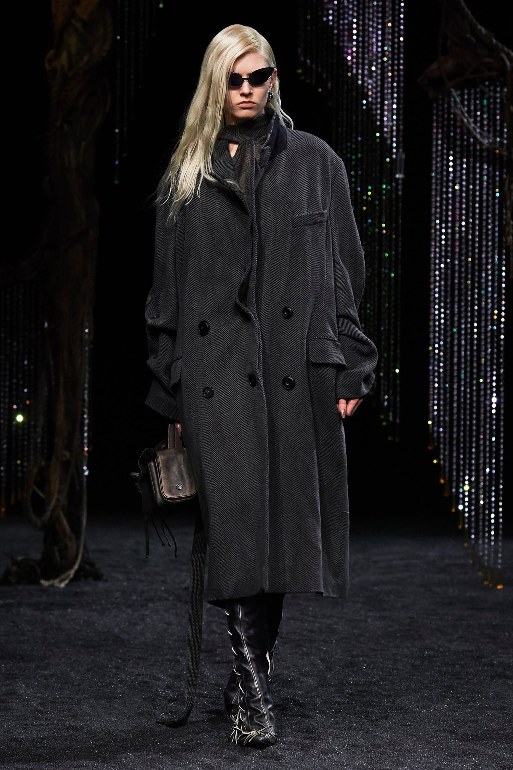 An oversized black wool coat with long sleeves and a collared design, featuring button details.