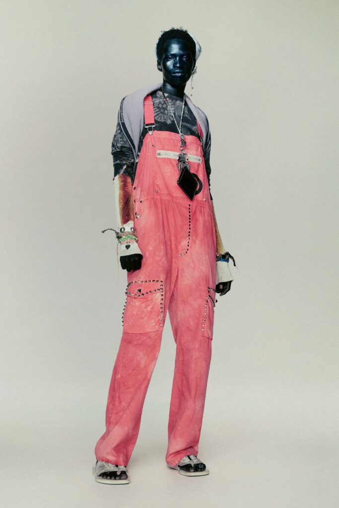 A relaxed fit pink denim overall with long sleeves and buttoned details.