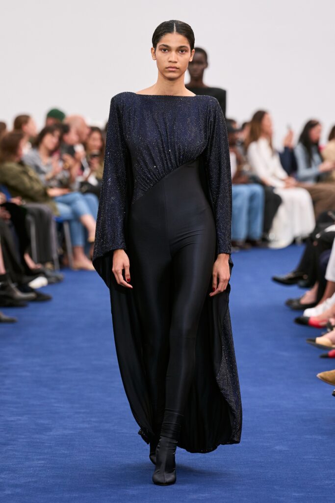A fitted black silk dress with long sleeves and an asymmetric design.