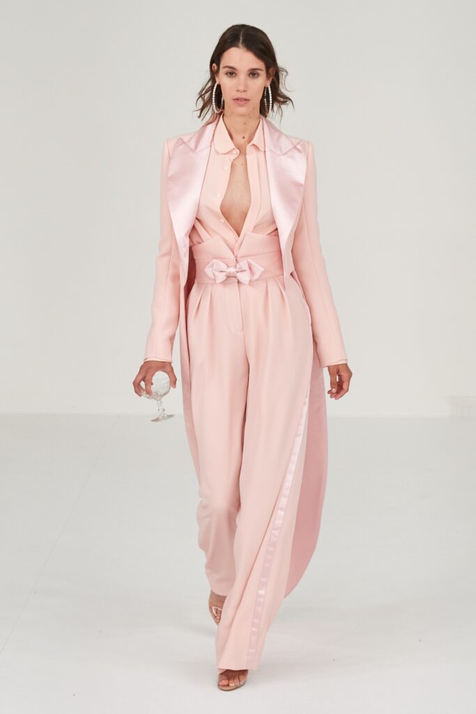 A fitted pink silk jacket with a V-neck and belted pants, layered for a chic look.