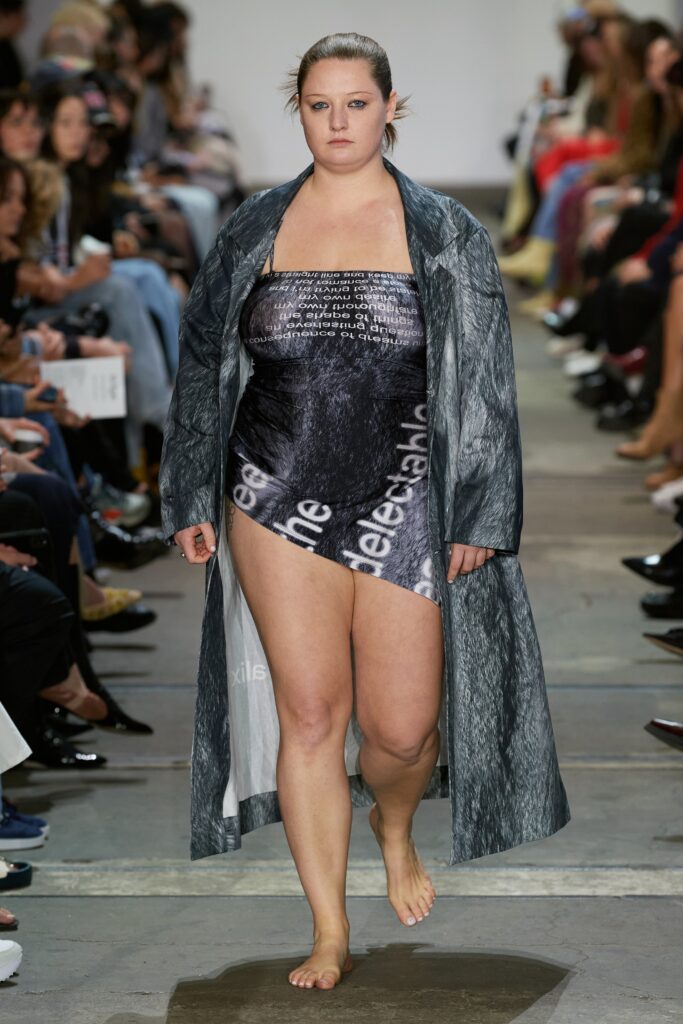 A fitted gray coat layered over a sleeveless black dress with an asymmetric design.