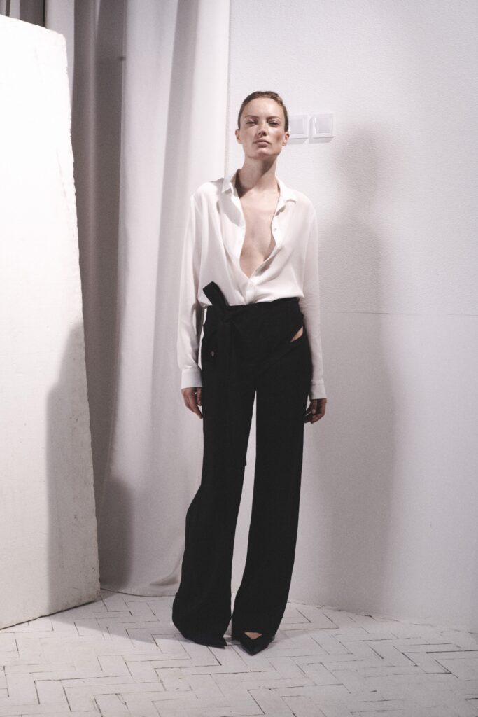 A relaxed white long-sleeve collared shirt paired with straight-leg black pants.
